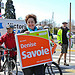 Denise wheeling a bike, with Jessica Vanderveen holding the sign at Earth Walk in Victoria.